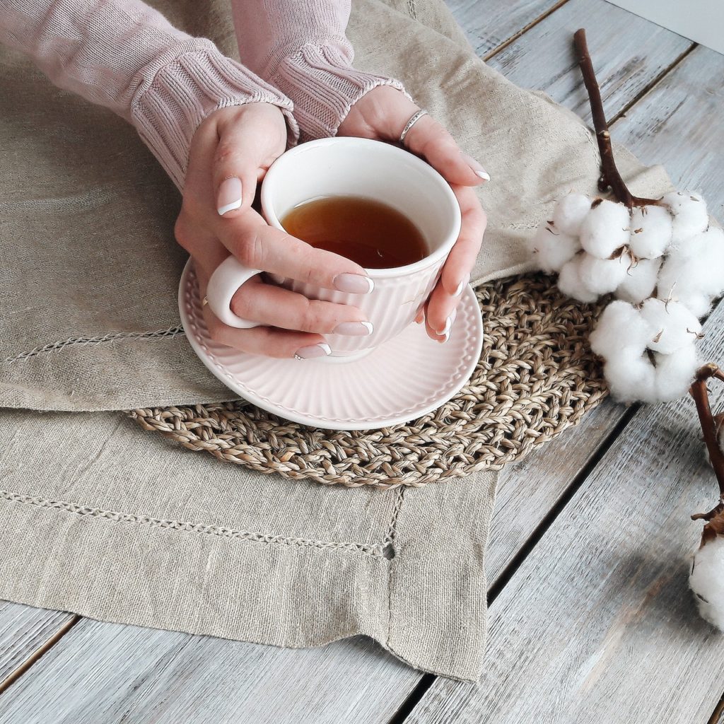 lady holding black tea in a white cup with her hands