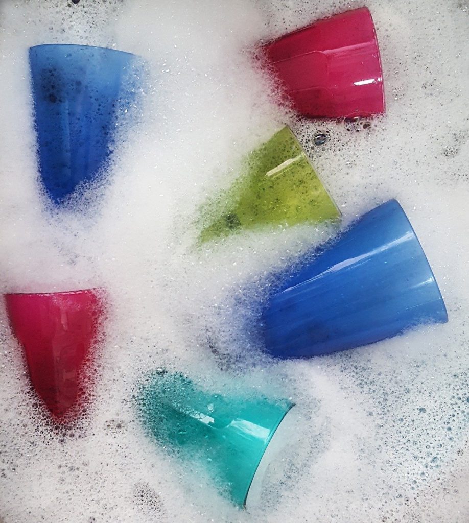 multicolour glasses kept in soap water for soaking and easy wash