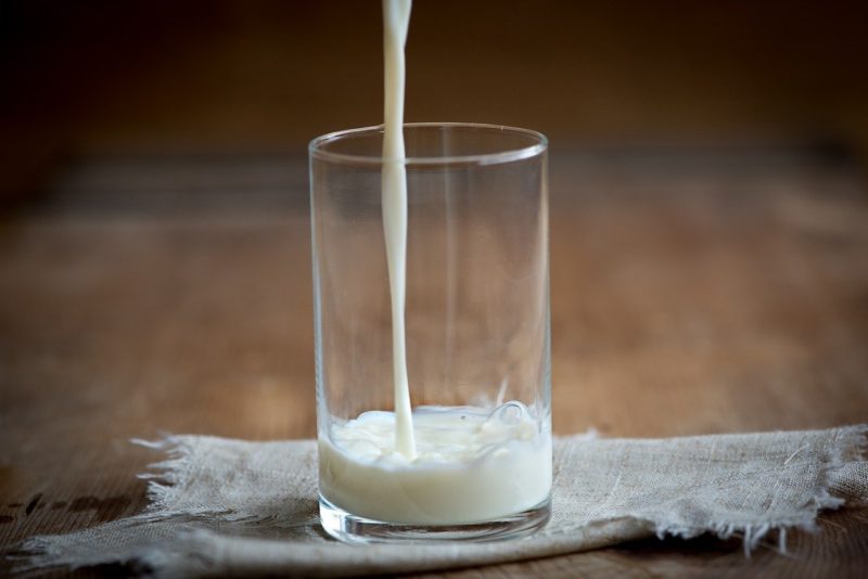 cow milk pouring into the glass container
